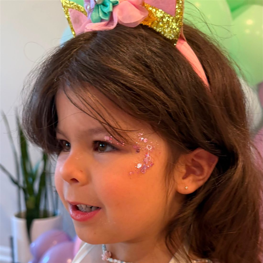 Girl with a unicorn headband and pink glitter face paint